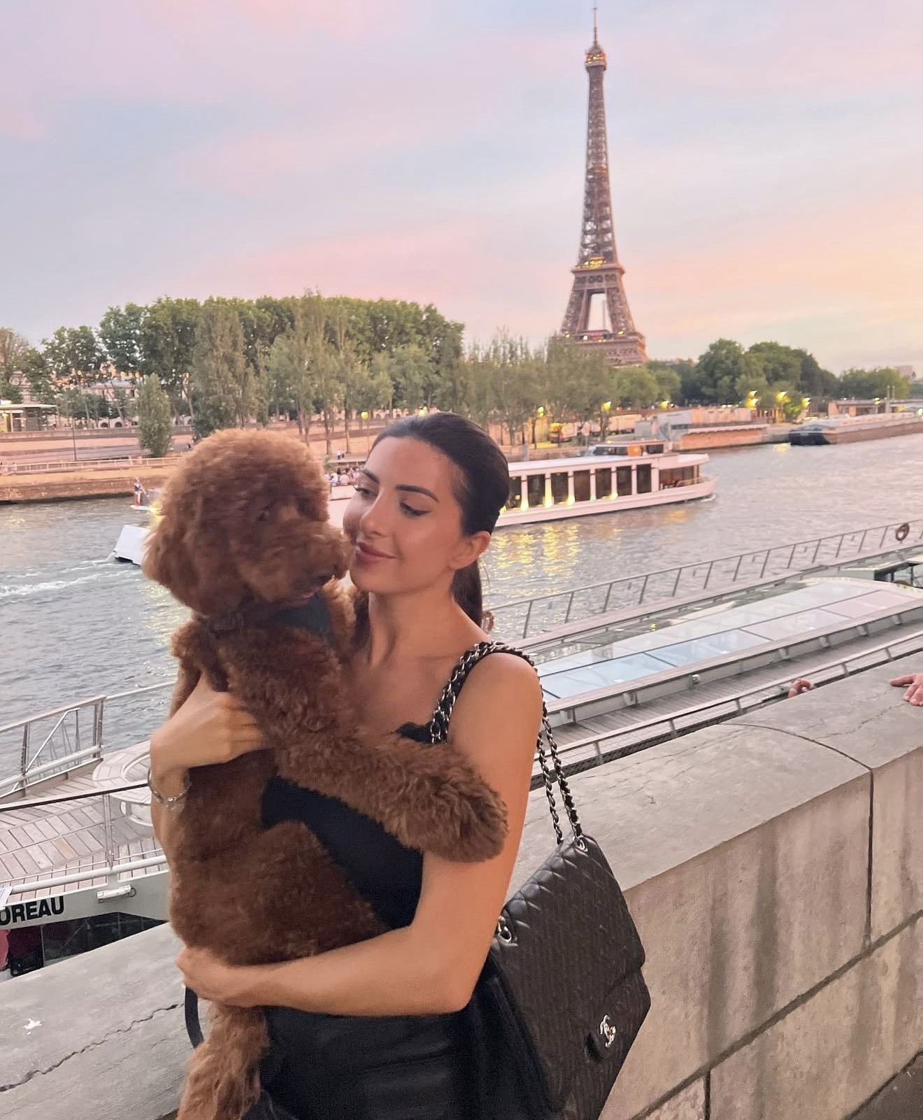 Daniella holding Cannolli on a Paris riverside at sunset, the Eiffel Tower behind them